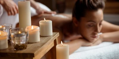 Young beautiful girl relaxing in spa salon. Focus on candles.